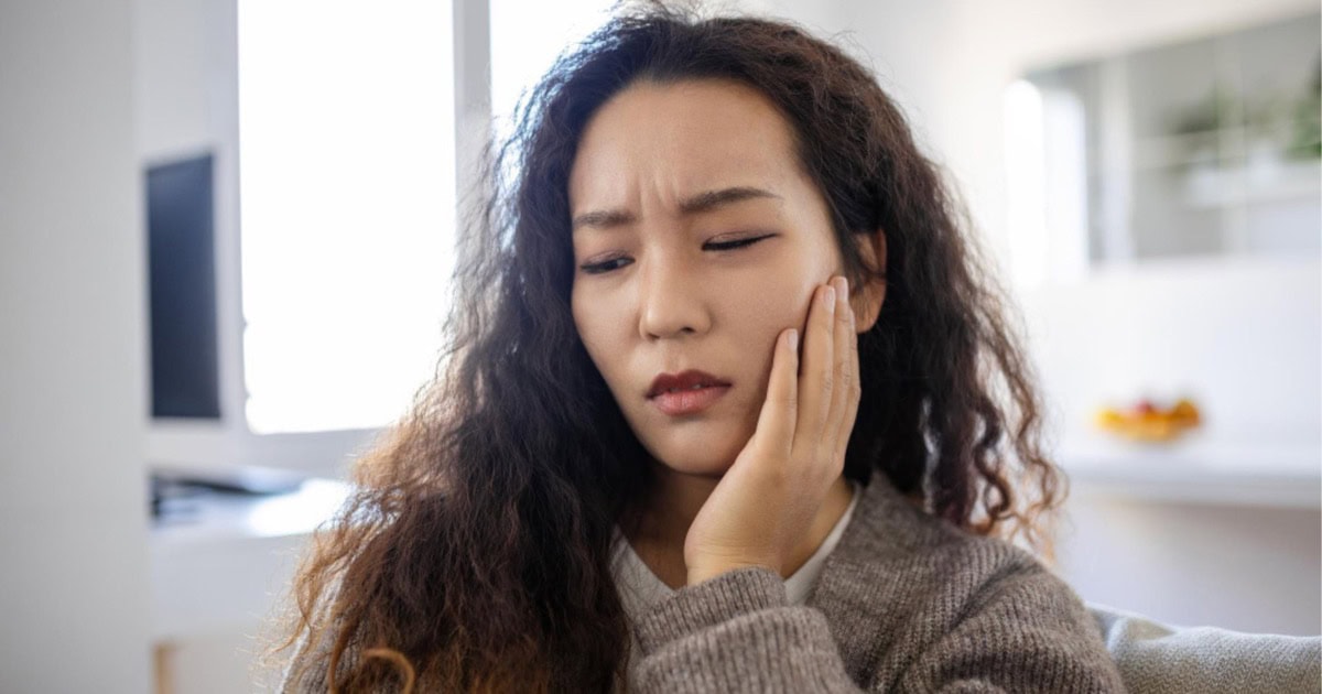 person touching their jaw in discomfort relevant to wisdom tooth symptoms in Yeronga
